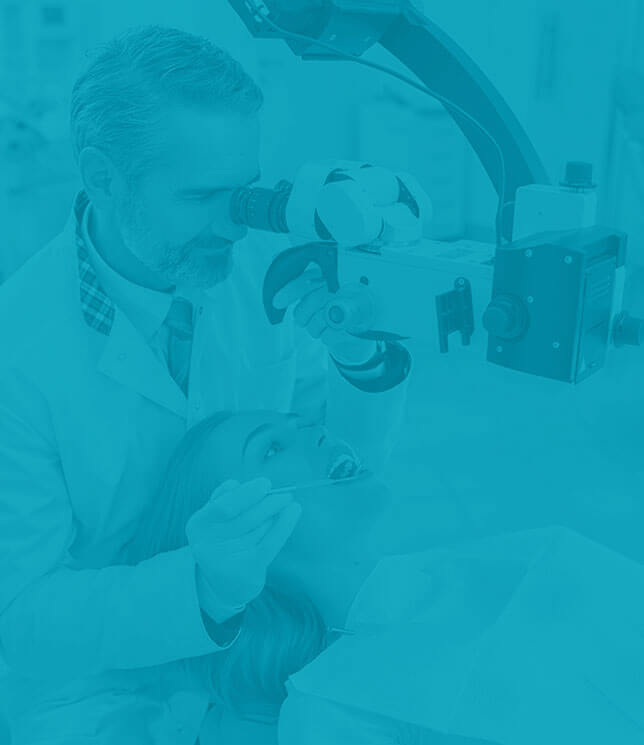 Zubár skúma cez prístroj zuby pacientky